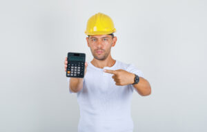 Builder man pointing finger at calculator in white t-shirt, helm